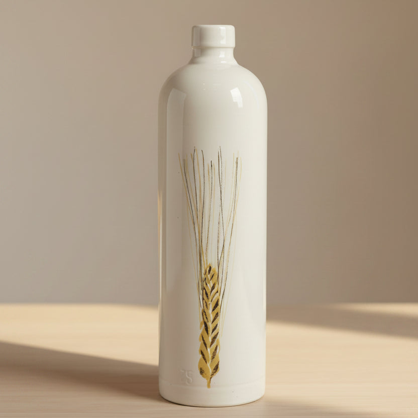 A tall, cylindrical ceramic bottle with a white glaze, featuring a painted golden wheat stalk design on the front