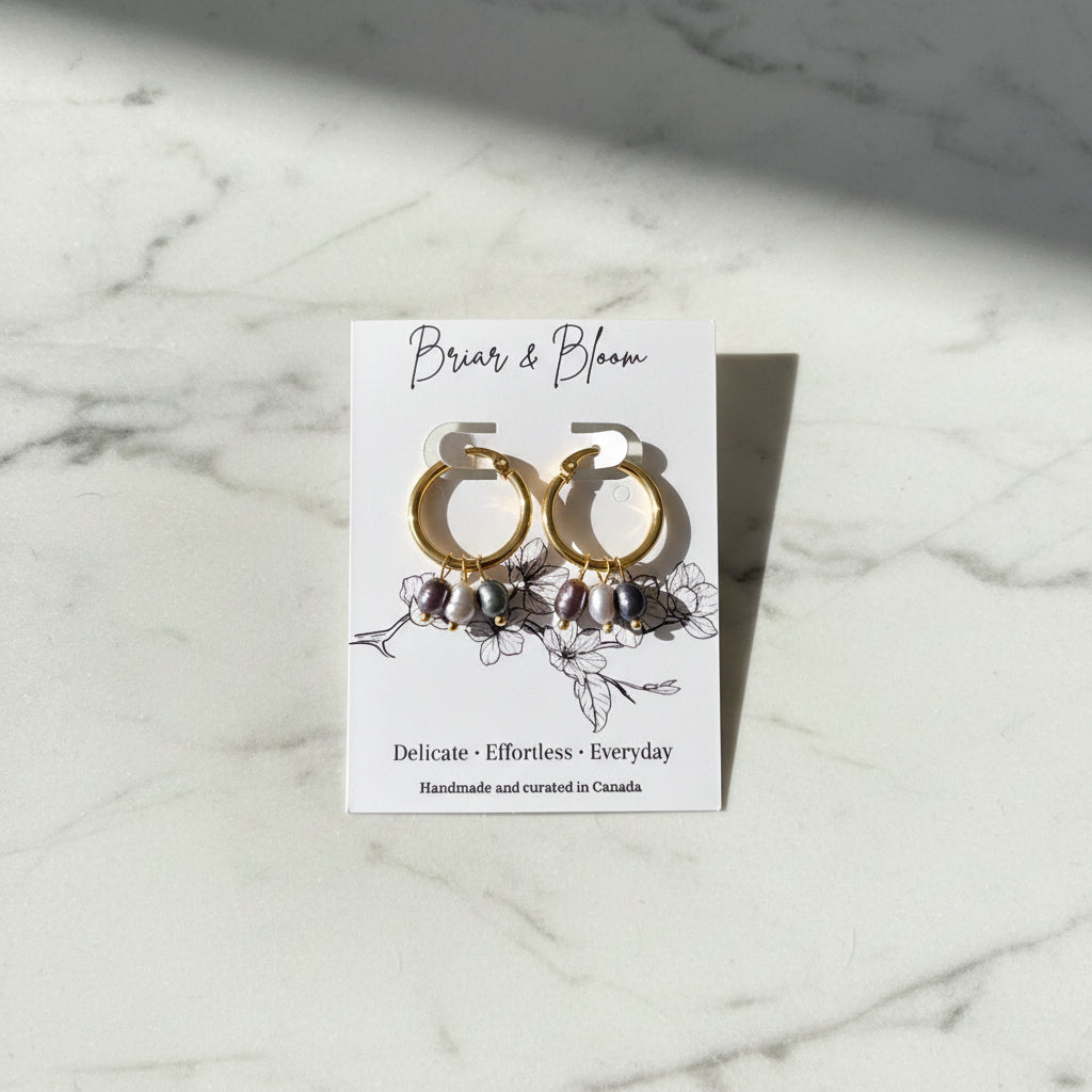 Gold hoop earrings with small dark gray beads.