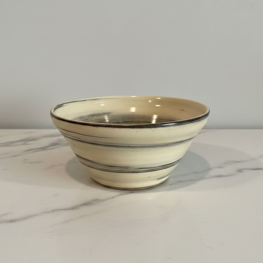 A handmade ceramic bowl dark brown horizontal stripes.