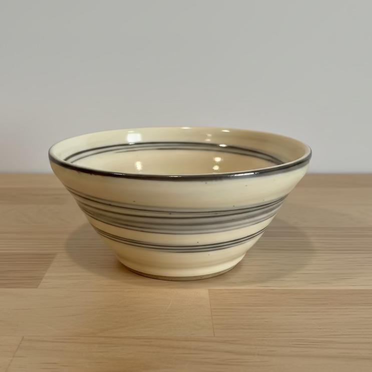 A handmade ceramic bowl dark brown horizontal stripes.