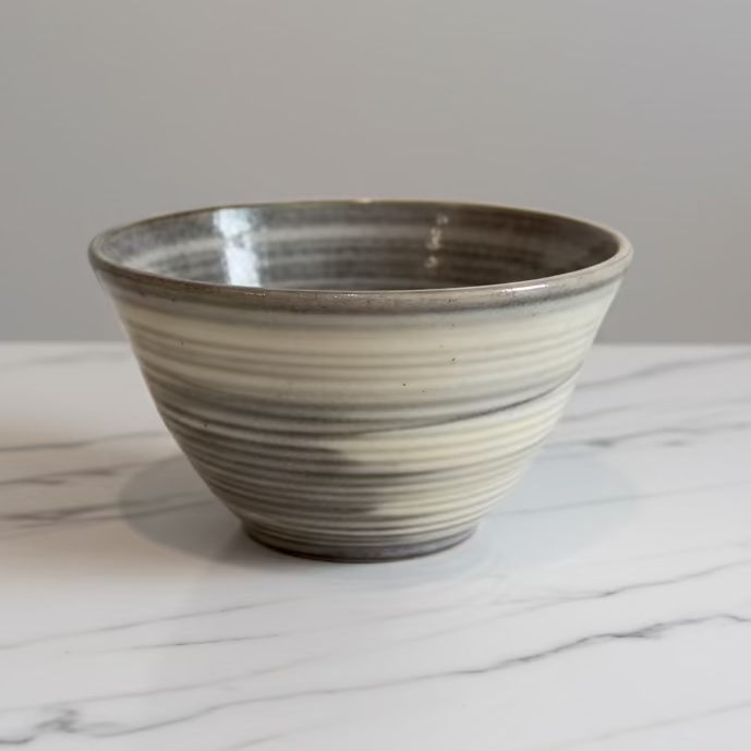 A handmade ceramic bowl with a rustic, hand-rolled texture and a glossy glaze.