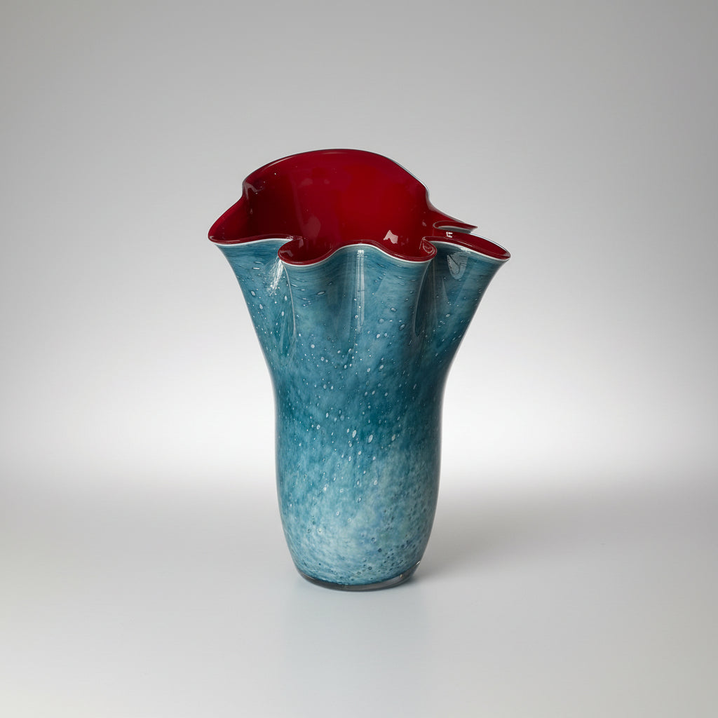 A blue and red blown glass vase with a speckled pattern.