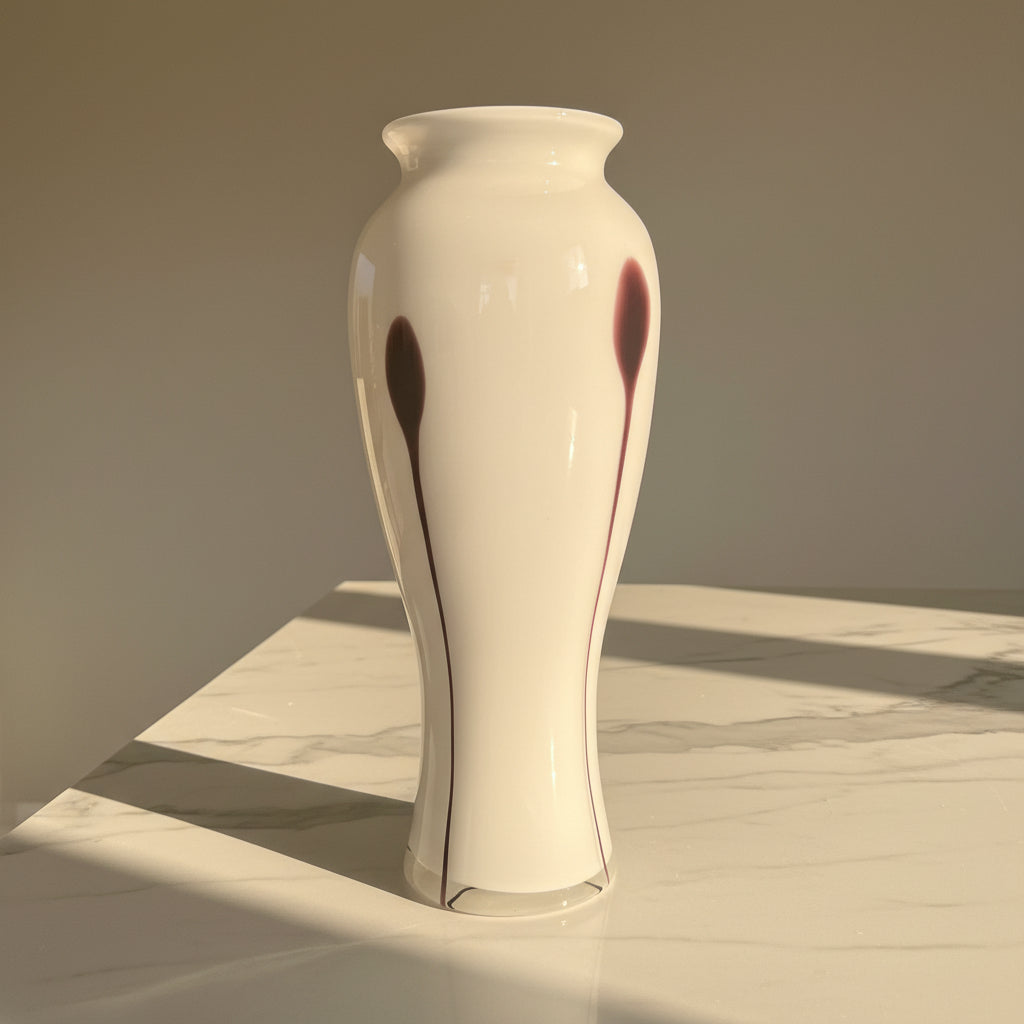 A tall white ceramic vase with dark plum streaks