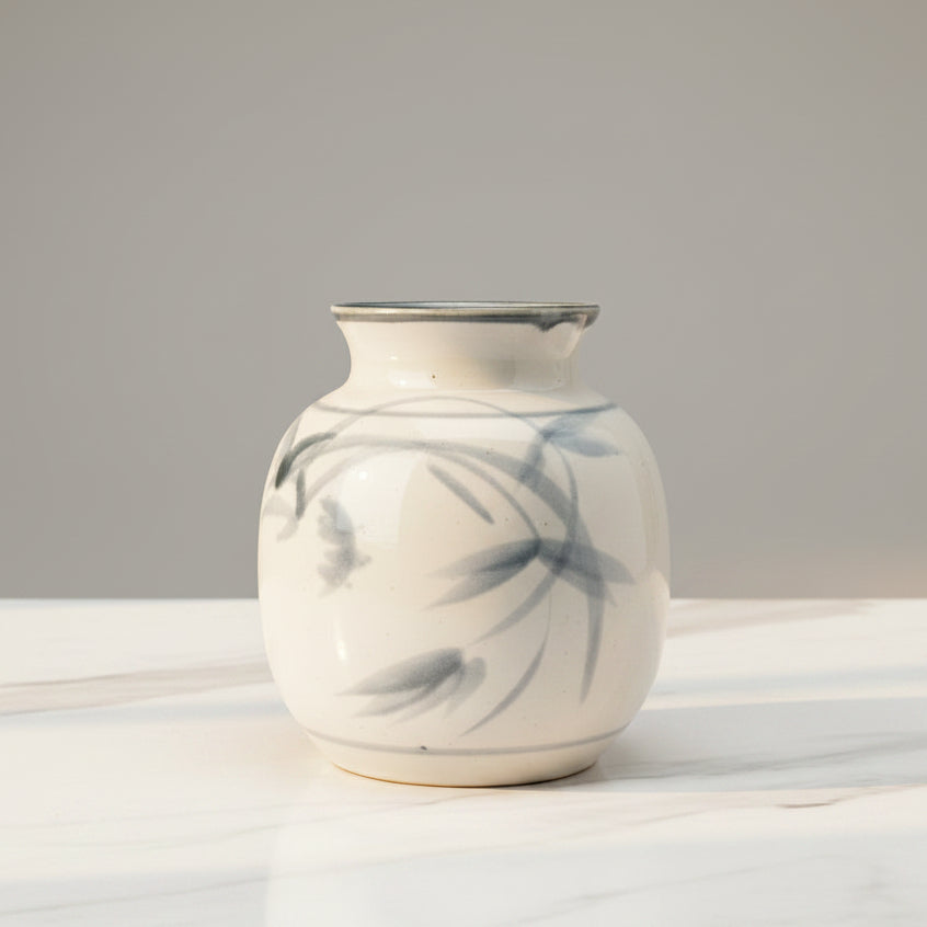 Small white ceramic vase with blue painted leaves