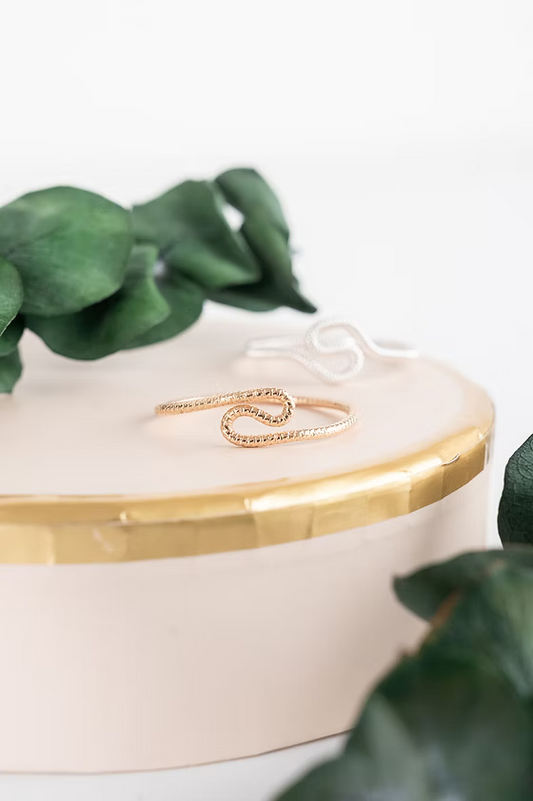 A gold snake-shaped ring with a textured pavé band.