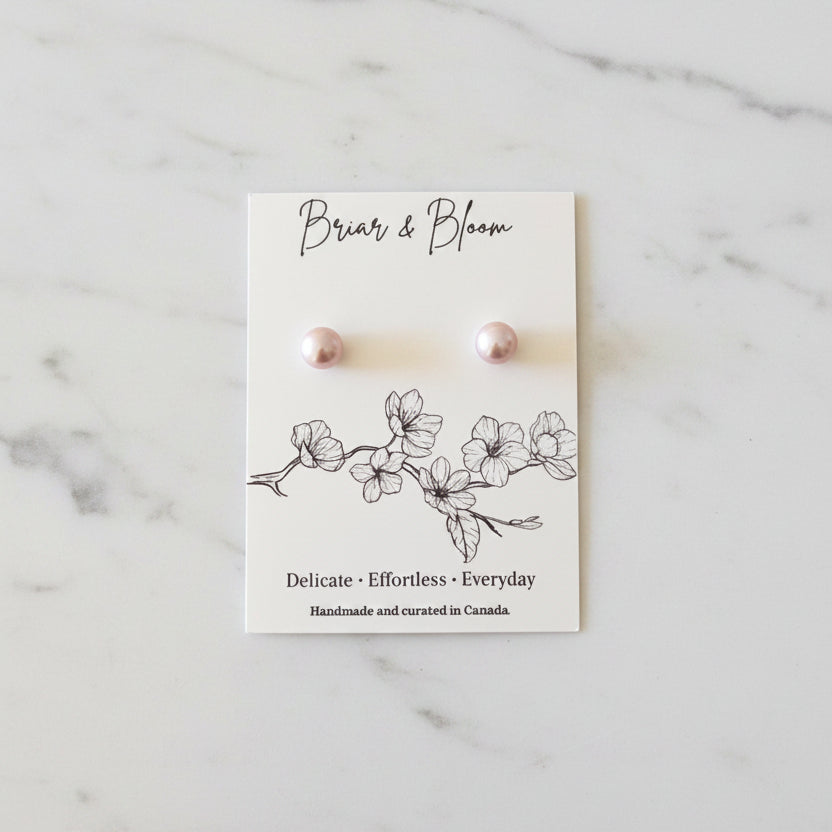 A pair of lavender pearl stud earrings.