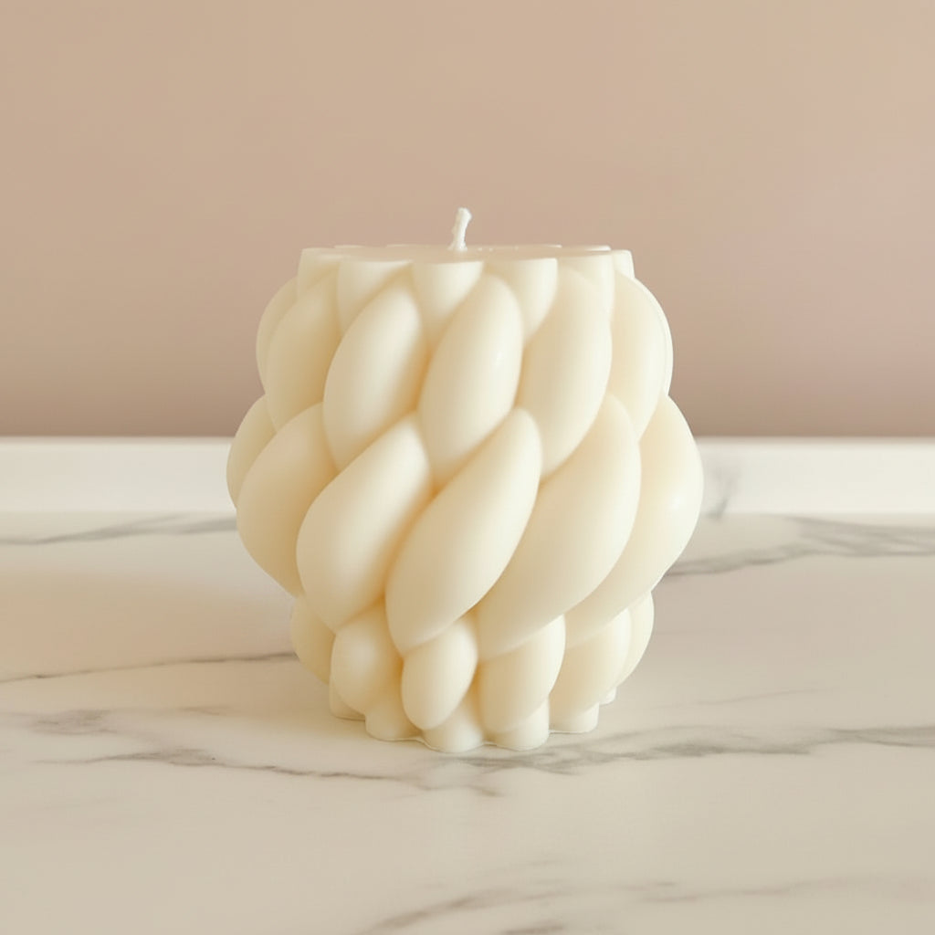A cream sculptural candle with a twisted design