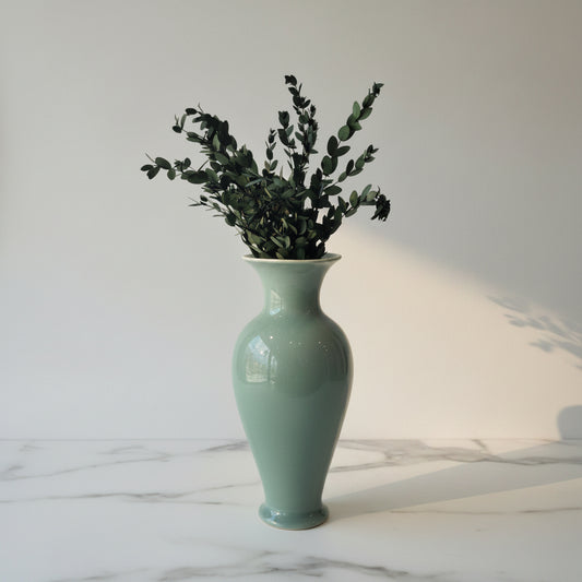 Green ceramic vase on counter with dried eucaplyptus