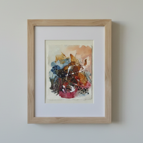 A framed abstract  painting with a light natural wood frame and white mat.