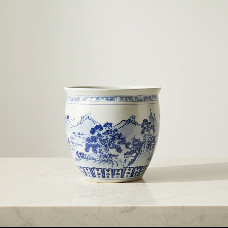 A large ceramic planter pot with a blue and white landscape design.