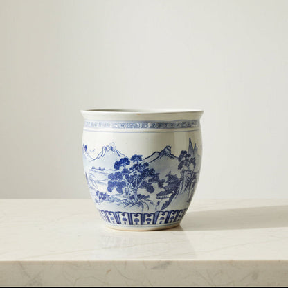 A large ceramic planter pot with a blue and white landscape design.