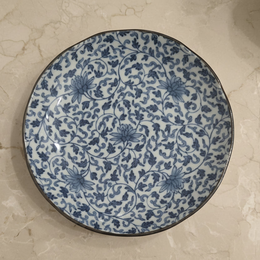 A round ceramic plate with a blue and white floral pattern.