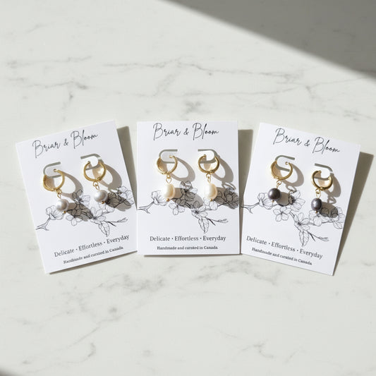 Three pairs of gold and pearl dangle earrings displayed.