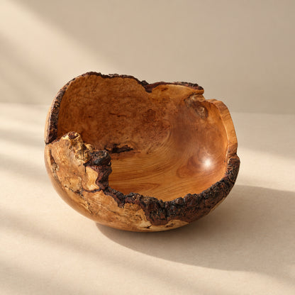 A handcrafted wooden bowl with a natural live-edge bark finish