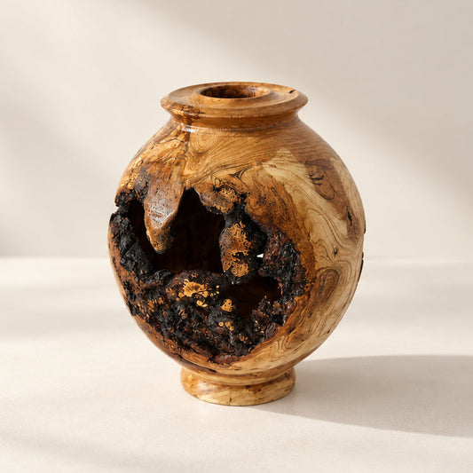 A small decorative vase made from a natural burl wood piece, featuring a rounded body, a short neck, and a hollowed-out dark section 