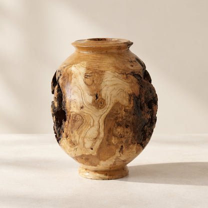 A small carved wooden vase with a rounded body, short neck, and natural bark edges