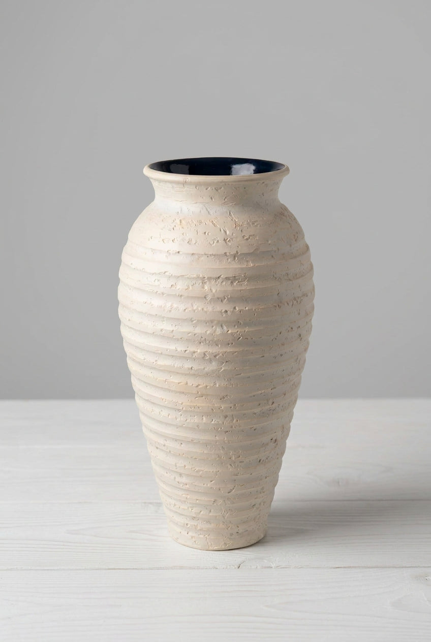 A tall, ribbed ceramic vase in a textured cream-beige finish with a glossy black interior.