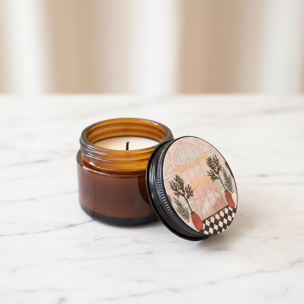 An amber glass jar candle with its black lid off, showing the white wax and wick. 