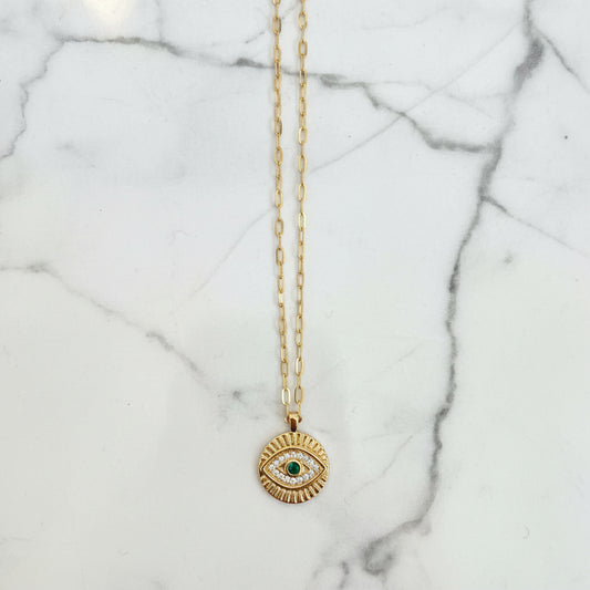 Gold necklace with an evil eye pendant on a marble surface