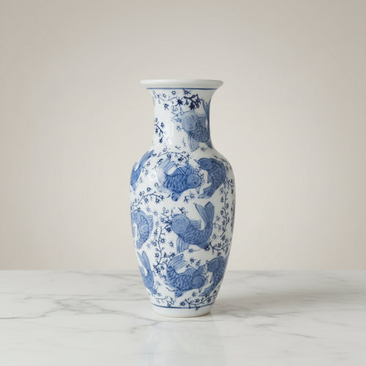 A small white ceramic vase with a blue floral and fish pattern.
