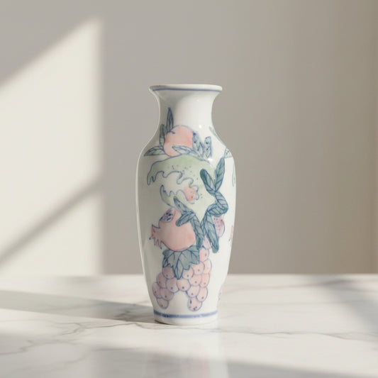 A white ceramic vase decorated with hand-painted a pink peache, pomegranate, grapes and green leaves