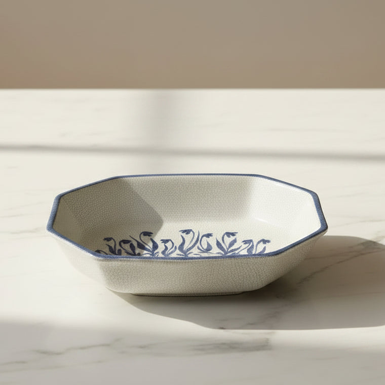 A ceramic serving dish with a textured off-white interior and a blue painted tulip motif