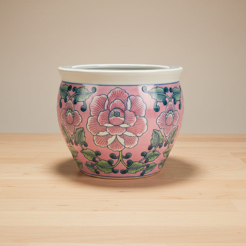 A round ceramic planter pot with a pink floral pattern, featuring large white and pink peony-like flowers with green leaves