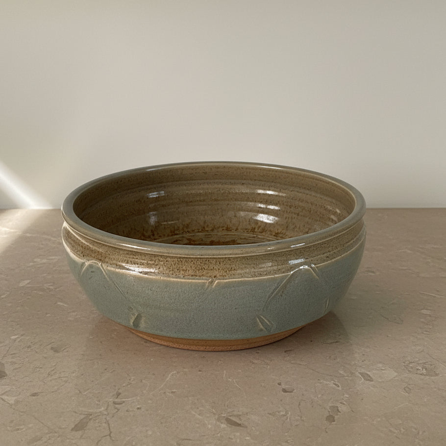 A large round ceramic bowl with a speckled brown and gray glazed finish