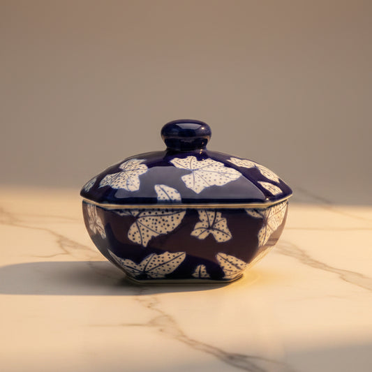 A small lidded ceramic container  with a deep cobalt blue glaze and white floral pattern