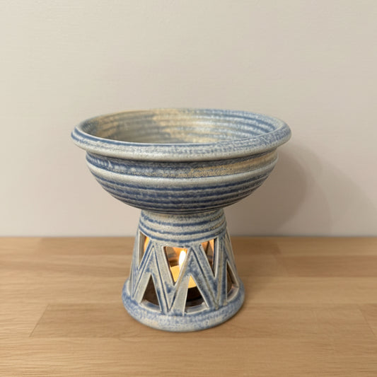 A handmade ceramic wax melt diffuser with a blue and white striped pattern