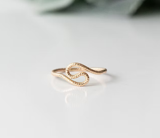 A gold snake-shaped ring with a textured pavé band.