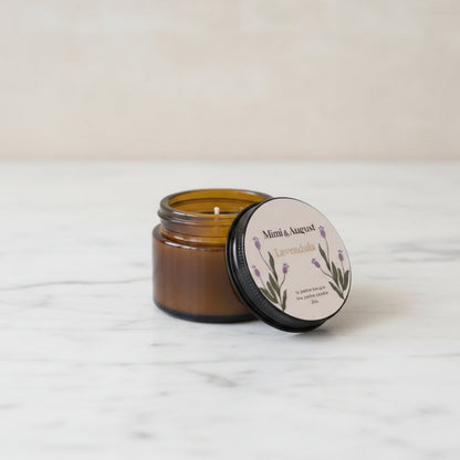 An amber glass jar candle with its black lid off, showing the wax and wix.