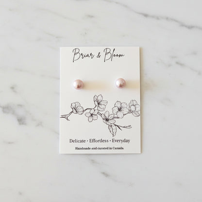 A pair of lavender pearl stud earrings.