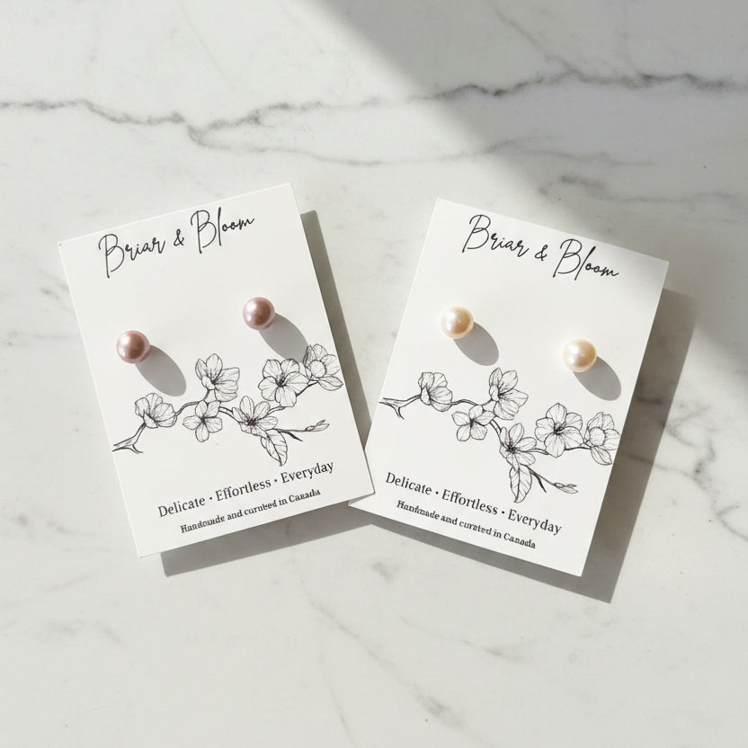 Two pairs of small pearl stud earrings.