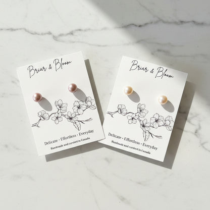 Two pairs of small pearl stud earrings.