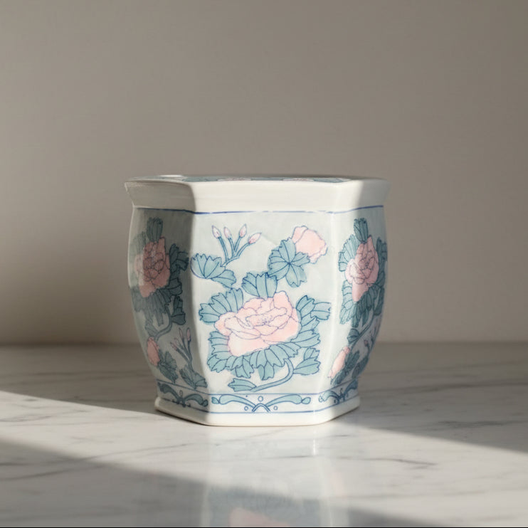 A hexagonal ceramic planter with a white glaze decorated with blue floral patterns and pink peonies.