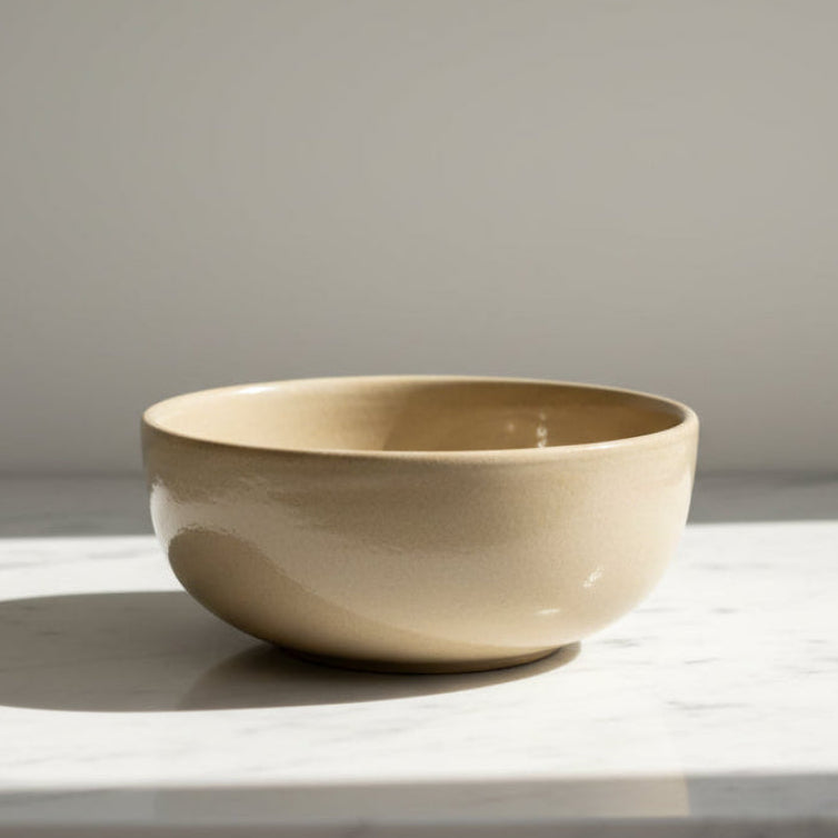 A minimalist beige ceramic bowl with a textured matte finish.