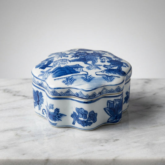 A small blue and white porcelain lidded box with a floral and landscape pattern.