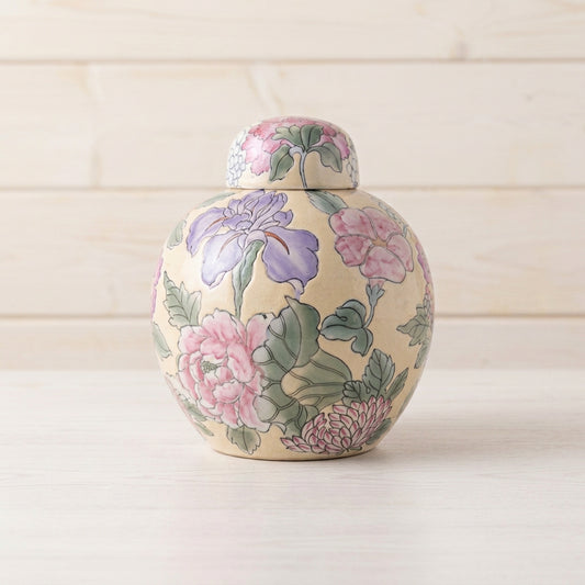 A small ceramic lidded jar with a floral hand-painted pattern in pink, purple, and green on a cream background.