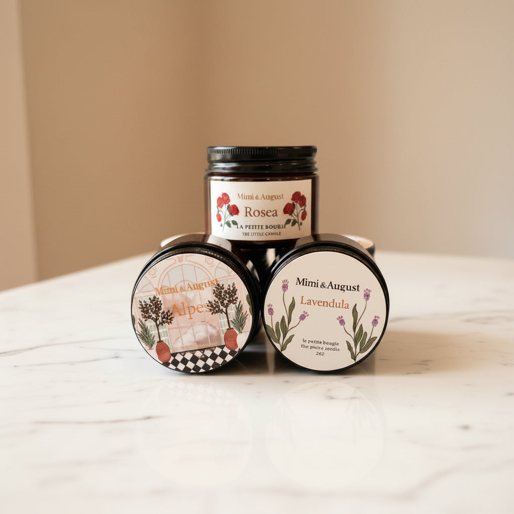 Three small glass candle jars with black lids.