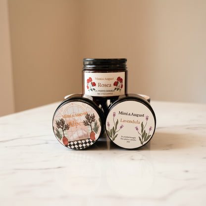 Three small glass candle jars with black lids.