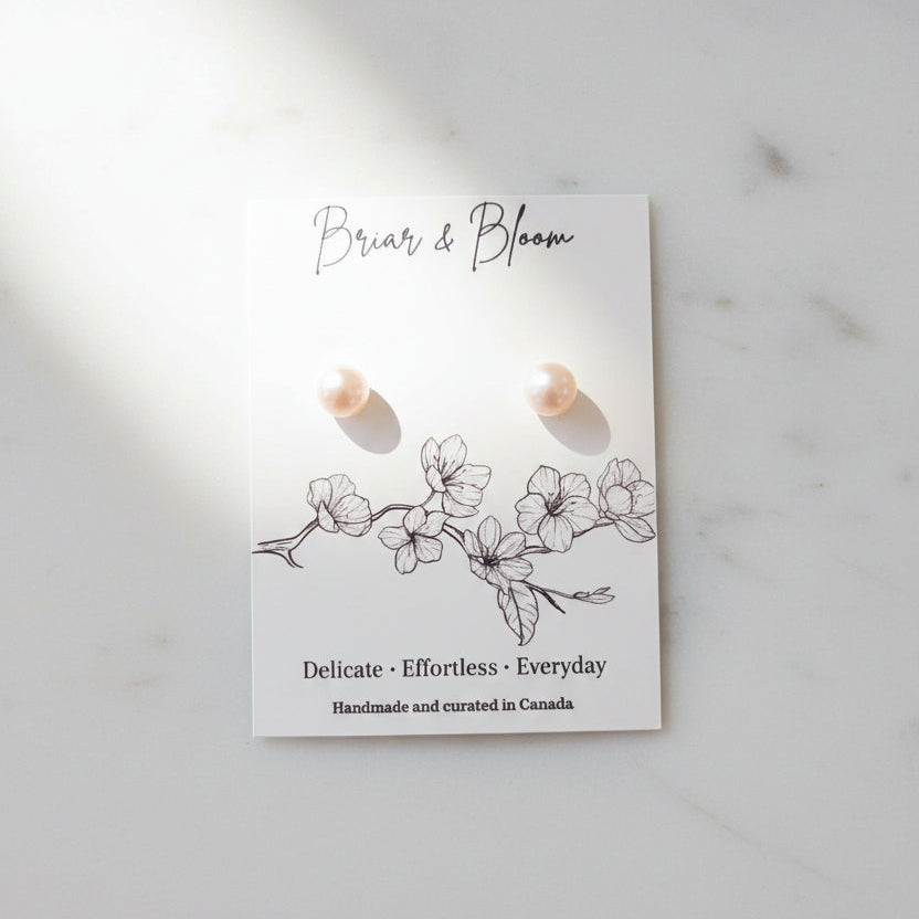 A pair of white pearl stud earrings.