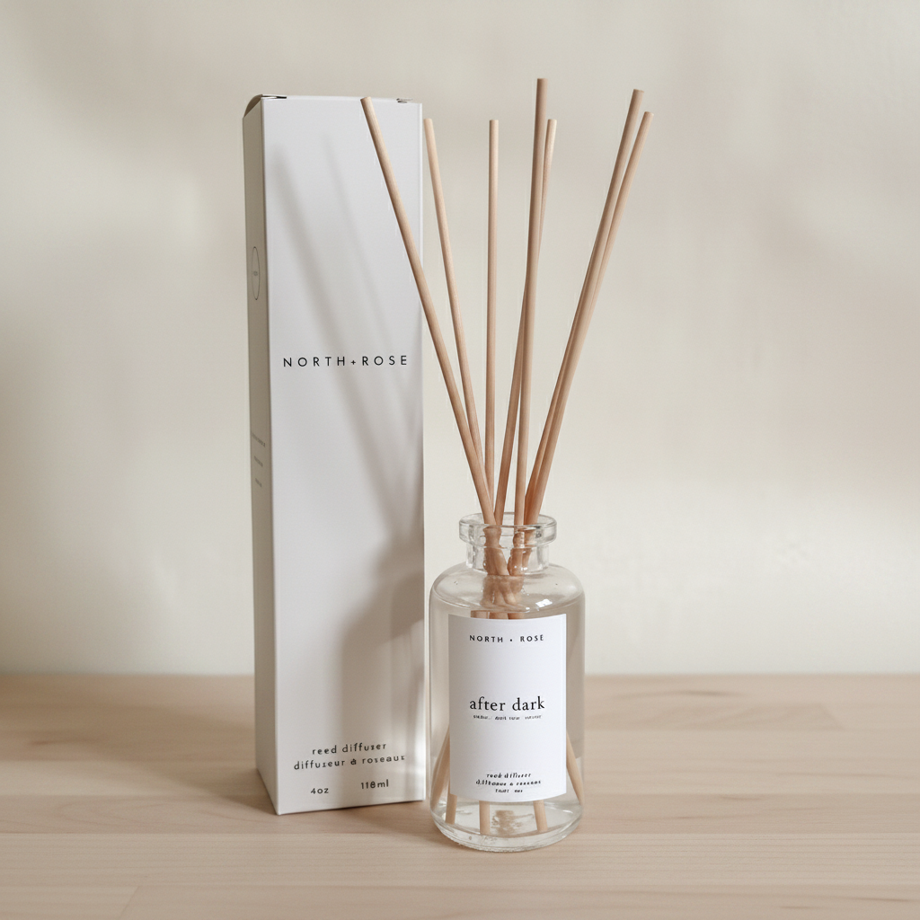 Reed diffuser set with clear bottle and wooden sticks, branded 'North + Rose', on a neutral background.